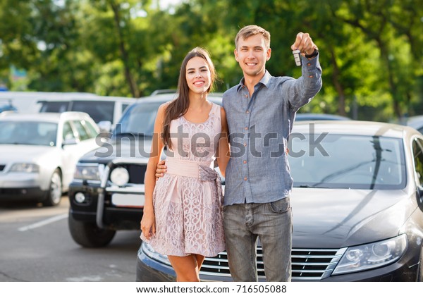 Buying used car. Car Dealer Inventory. Used\
cars store. Male wants to buy the car. Close-up of hand with a\
wrist watch, holding key from auto, finance for car concept. Happy\
life. Blurred\
background.