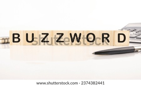 Buzzword - word word assembled from wooden cubes next to a calculator, pen and notepad