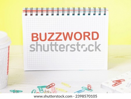 Buzzword the word is written on a blank sheet in a notebook standing on a table on a yellow background
