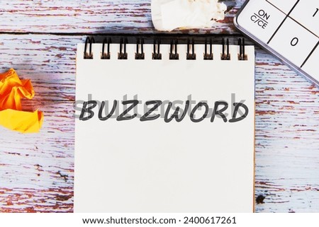 Buzzword - word written on a sheet of notebook lying on old vintage boards with a calculator and folded paper