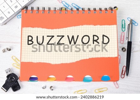 Buzzword word is written on a sheet in a cage lying on a notebook on the table next to stationery