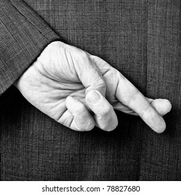 A B/W Conceptual Image Of A Business Man With His Fingers Crossed Behind His Back.