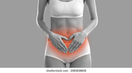 BW image of woman suffering from acute menstrual pain. Black and white banner with woman in underwear having severe period cramps standing on grey background holding hands on red inflamed stomach area