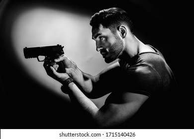 Bw Portrait Of Serious Young Man Holding Gun On Dark Background