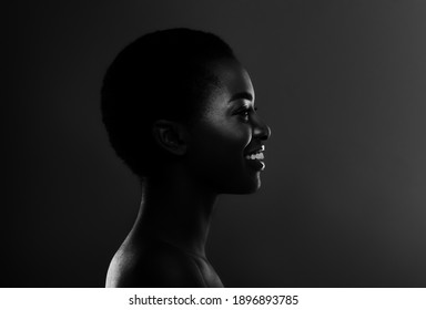 Bw Profile Portrait Of Smiling Black Woman In Backlit Standing Over Dark Background, Side View Of Beautiful African American Female With Short Haircut, Monochrome Shot, Copy Space