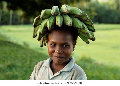 BWAGAOIA, PNG - JULY 12: Unidentified Melanesian Child Transporting Bananas On Head. July 12, 2009, Bwagaoia, Misima Island, Papua New Guinea