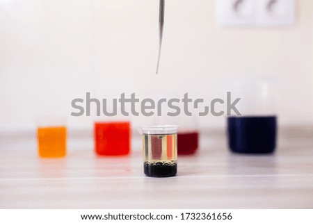 By adding drops of coloured water to a beaker with oil. Science experiment