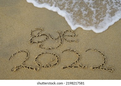 Bye 2022 Text Message Handwritten On Sand Background. Holiday Postcard Template.