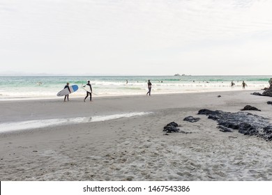 BYRON BAY, AUSTRALIA - SEPTEMBER 20, 2014: Surfers walking towards the water or waiting to catch a wave at Wategos Beach, Byron Bay, NSW, Australia
