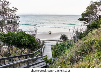 BYRON BAY, AUSTRALIA - SEPTEMBER 20, 2014: Two surfers carrying their surfboards and walking along the shore at Wategos Beach, Byron Bay, NSW, Australia