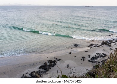 BYRON BAY, AUSTRALIA - SEPTEMBER 20, 2014: Surfers riding a wave or waiting to catch a wave at Wategos Beach, Byron Bay, NSW, Australia