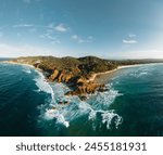 Byron Bay lighthouse and the pass high on the rocky headland - the most eastern point of Australian continent facing Pacific ocean in elevated aerial seascape above coast.