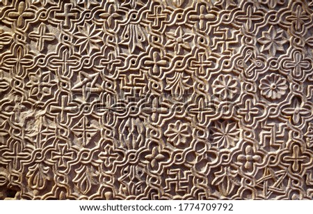 Byzantine ornament, pattern carved in old stone wall, ancient texture background, detail of interior with geometric relief. Decoration of Roman Greek architecture. Theme of antique, wallpaper, symbol.