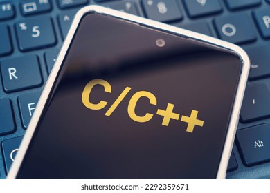 C Programming language for mobile development, concept. Smartphone on the laptop keyboard, the programmer workplace. inscription on the mobile phone screen ,
