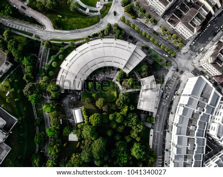 C shape building architechture surrounded by trees from top down aerial view