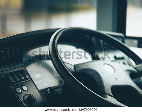 The\
cab of a bus with the steering wheel and\
dashboard.