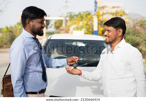 Cab driver receiving car key from bank\
officer in front of car - concept of financial support from bank,\
starting new business and money\
loan.