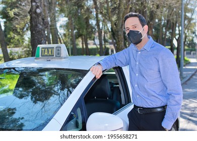 Cab Driver Waiting For The Customer Next To His Cab Wearing A Black Mask.