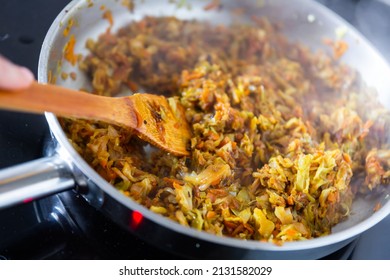 Cabbage in frying pan on electric stove, process of stewed cabbage preparation