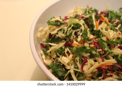 Cabbage Slaw Mix With Raw Kale, Carrots And Craisins All In A White Salad Bowl.