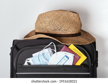 A Cabbin Bag Prepared To Travel During Pandemic Times With Facemask, Covid Test, Vaccination Card And Passport And Sun Hat, Concept Shot Of New Normal: A Travel Set During Pandemia