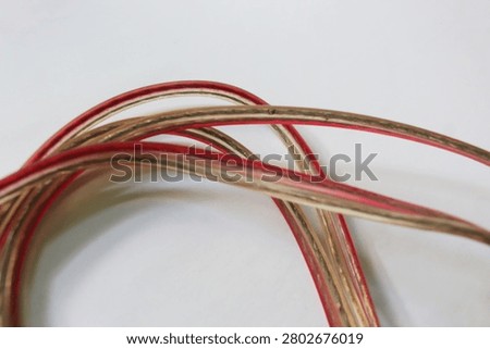 The cabel roll with a red and white outside functions to channel electricity from the power source to electronic devices, such as TV, iron, computer and devices. 