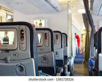 Cabin Airliner, Blue Leather Seats With Multimedia System, Passage Between The Seats. Blurred Background, Flight Attendant Doing Pre-flight Training