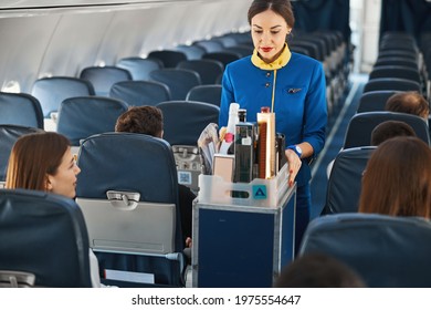 Cabin Attendant Leading Trolley Cart Through Plane Aisle