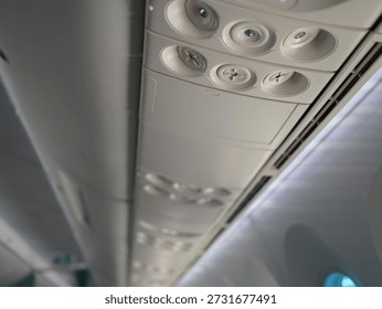 The cabin ceiling of the plane with AC control dial, reading lamp light and flight attendant calling button. Airplane interior in plane corridor.