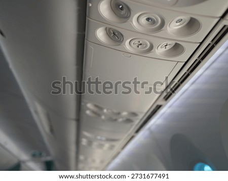 The cabin ceiling of the plane with AC control dial, reading lamp light and flight attendant calling button. Airplane interior in plane corridor.