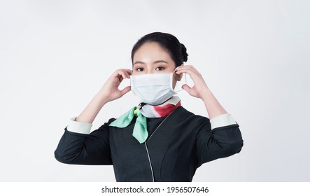 Cabin Crew Or Air Hostess With Face Mask In Covid 19 Pandemic. Flight Attendant Wear Medical Mask To Prevent Coronavirus Infection. New Normal Lifestyle In Airline Business. Pretty Stewardess Woman.