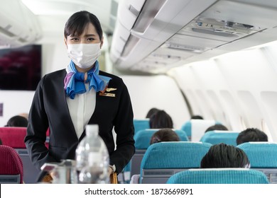 Cabin Crew Pushing Service Cart And Serve To Customer On The Airplane During Flight. New Normal, Flight Attendant And All Passengers Wearing Face Mask To Prevent COVID Infection During Virus Pandemic.