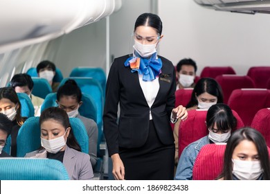 Cabin Crew Walking Around To Check Safety On The Airplane Before Plane Taking Off. New Normal, Flight Attendant And All Passengers Wearing Face Mask To Prevent COVID Infection During Virus Pandemic.