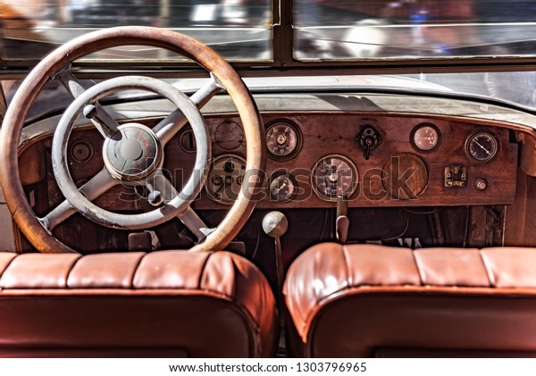 Cabin from inside a retro car. Wooden dashboard\
and steering wheel.
