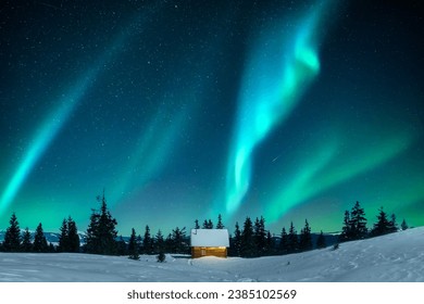 A cabin nestled amidst snow-covered fir trees on a mountain clearing in the winter. Aurora borealis. Northern lights in winter forest. Christmas holiday and winter vacations concept - Powered by Shutterstock