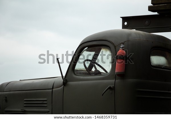cabin of an old military heavy truck with a red\
fire extinguisher on\
board