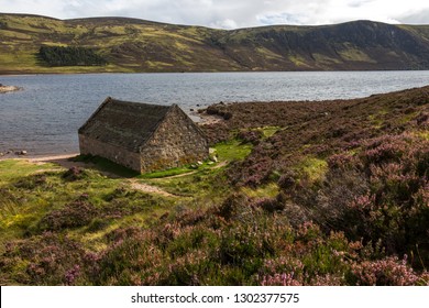 Cabin In The Scottish Highlands Overlooking A Big Lake On The Moor