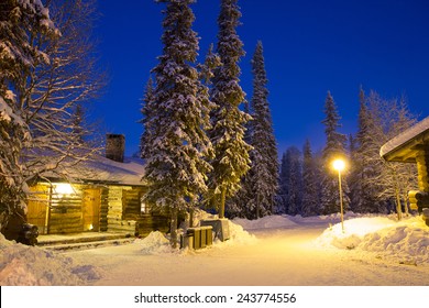 Cabin In The Woods By Night Between Snowed Pine Trees, Lapland Finland