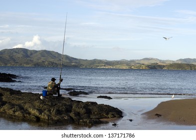 CABLE BAY,NZ - APR 22 2013:Mature Maori Man Fishing From The Beach.New Zealand Exclusive Economic Zone Covers 4.1 Million Square Kilometers And It's The Sixth Largest Zone In The World.