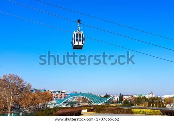 Cable car above Peace Bridge or Glass bridge\
crossing Kura river in the heart of Tbilisi, Georgia. Experience\
travel, thing to do in\
Tbilisi.