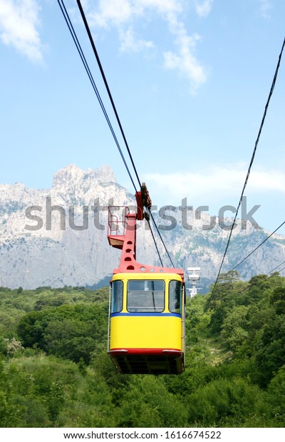 Cable car cabin on a\
mountain background. The rise of the cable car to the mountains in\
the summer.