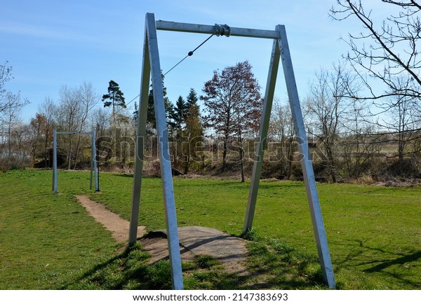 cable car for children on the playground. the child
sits hung on a rope and goes downhill on a pulley on a stretched
rope, cable car. a grassy meadow with two gates and a hill from
which to start