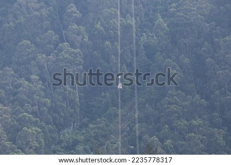 Cable car going down from Monserrate with forest background. Touristic activity in Bogota. Selective focus.