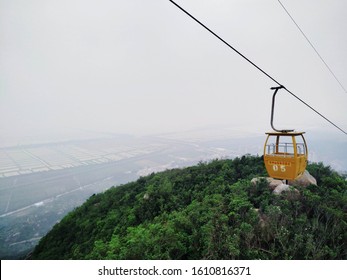 Cable car going up in Shenshan in Jiangmen, China. The text on the cable car says '神山缆车欢迎您', which reads 'Welcome to Shenshan Cable Car'.  