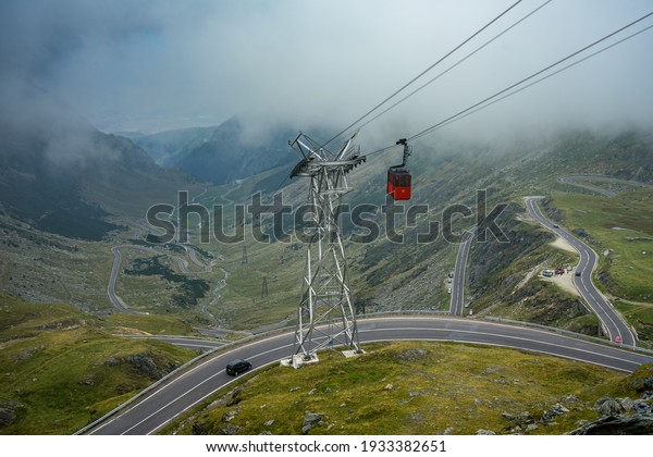 A cable car hangs over the Transfăgărășan in Romania\
on a cloudy day.