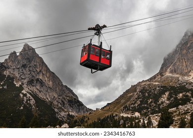 Cable car Lagazuoi Dolomiti from Passo di Falzarego to the Mount Lagazuoi. Bright red gondola between two mountains. Falzarego Pass, near Cortina d'Ampezzo. Belluno, Italy.