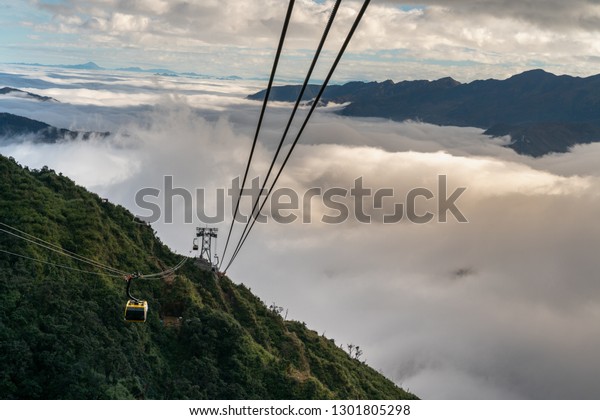 The cable car to mountain top with low clouds and\
mountain view