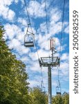 cable car in the mountains on a blue cloudy sky background. Communication tower on a cable car support