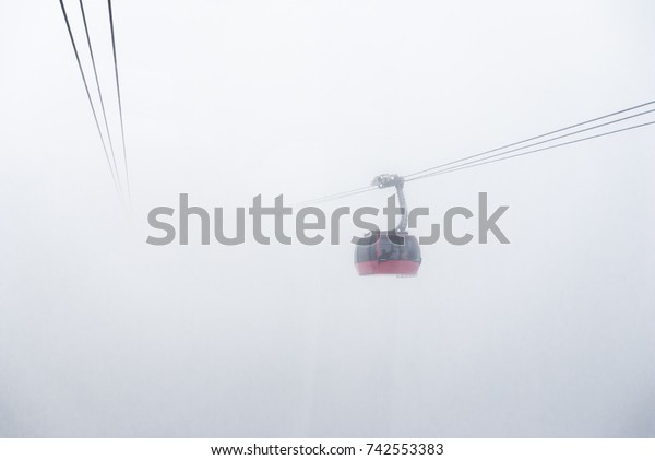 Cable car running between two snow covered\
mountains at a ski resort