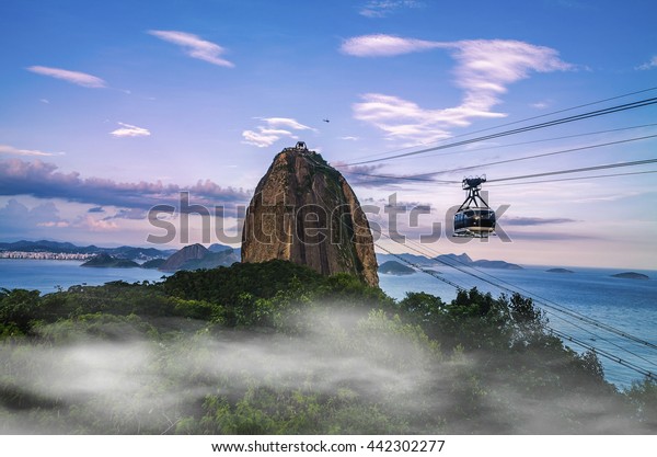 Cable car and Sugar Loaf mountain at sunrise with\
fog, Rio de Janeiro
